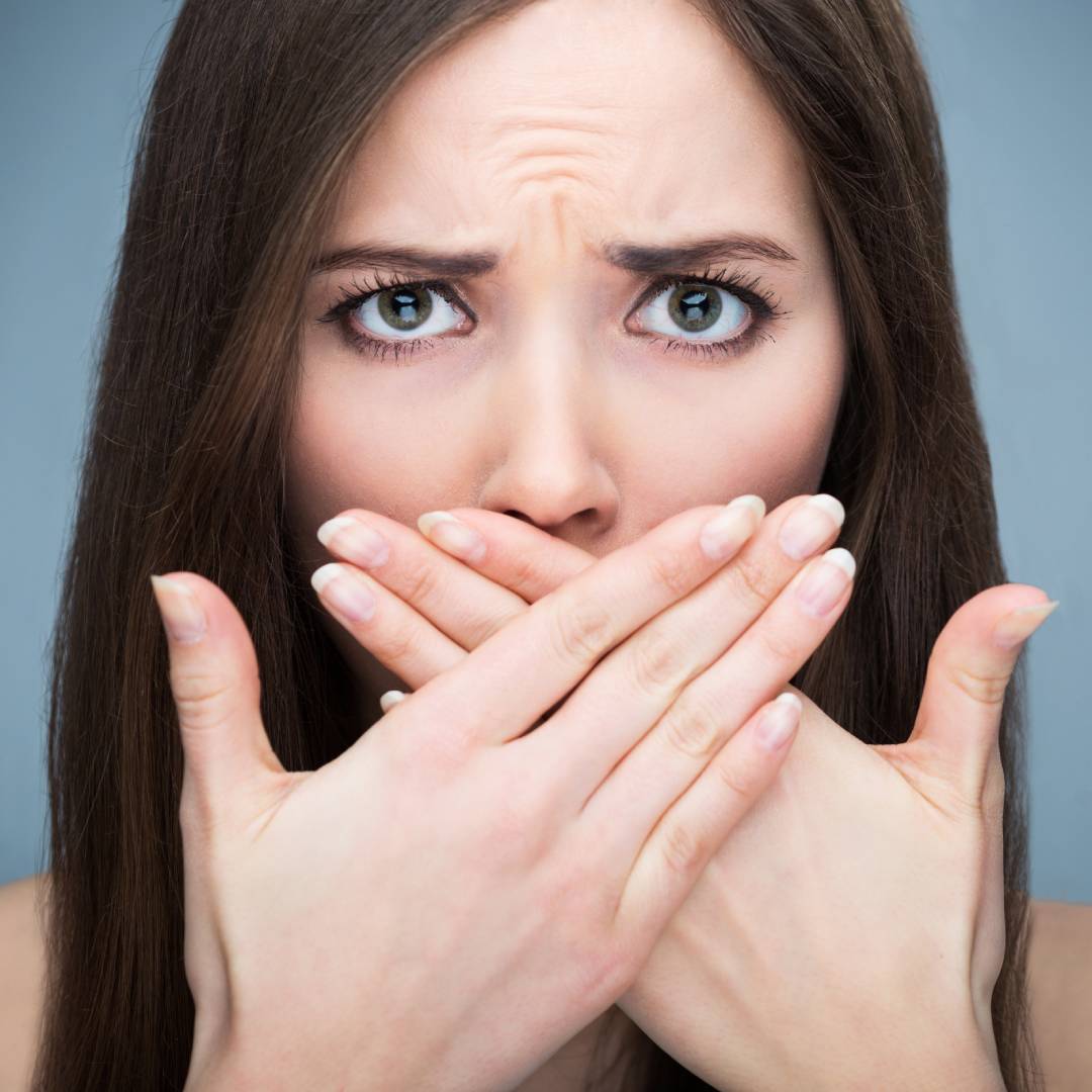 woman with bad breath holding hands up to her face