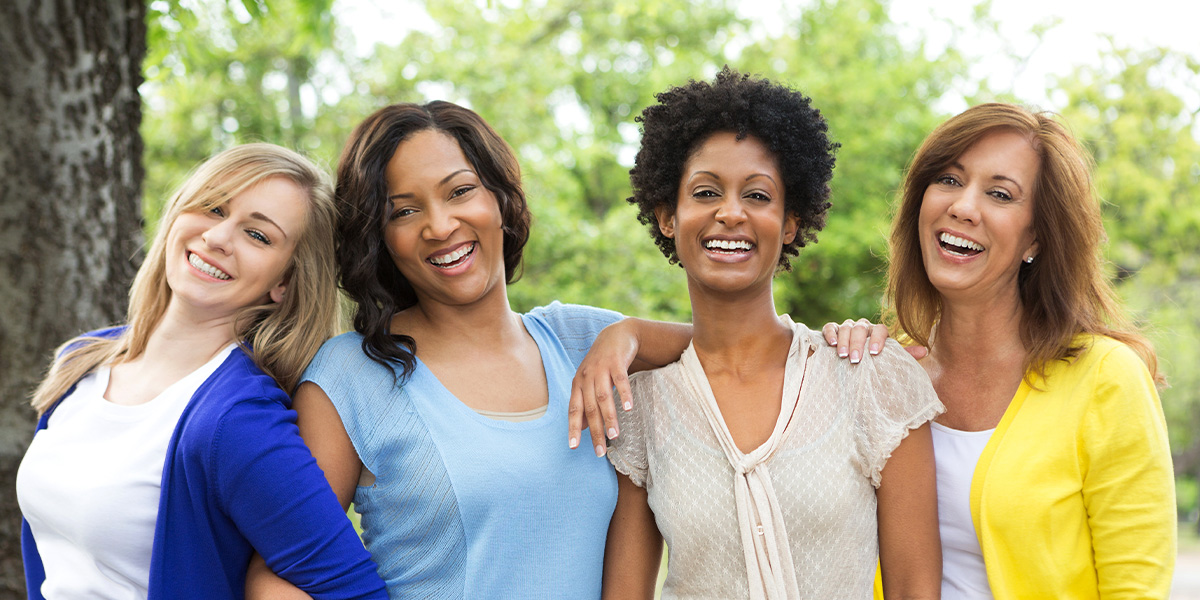 group of four diverse women smiling together